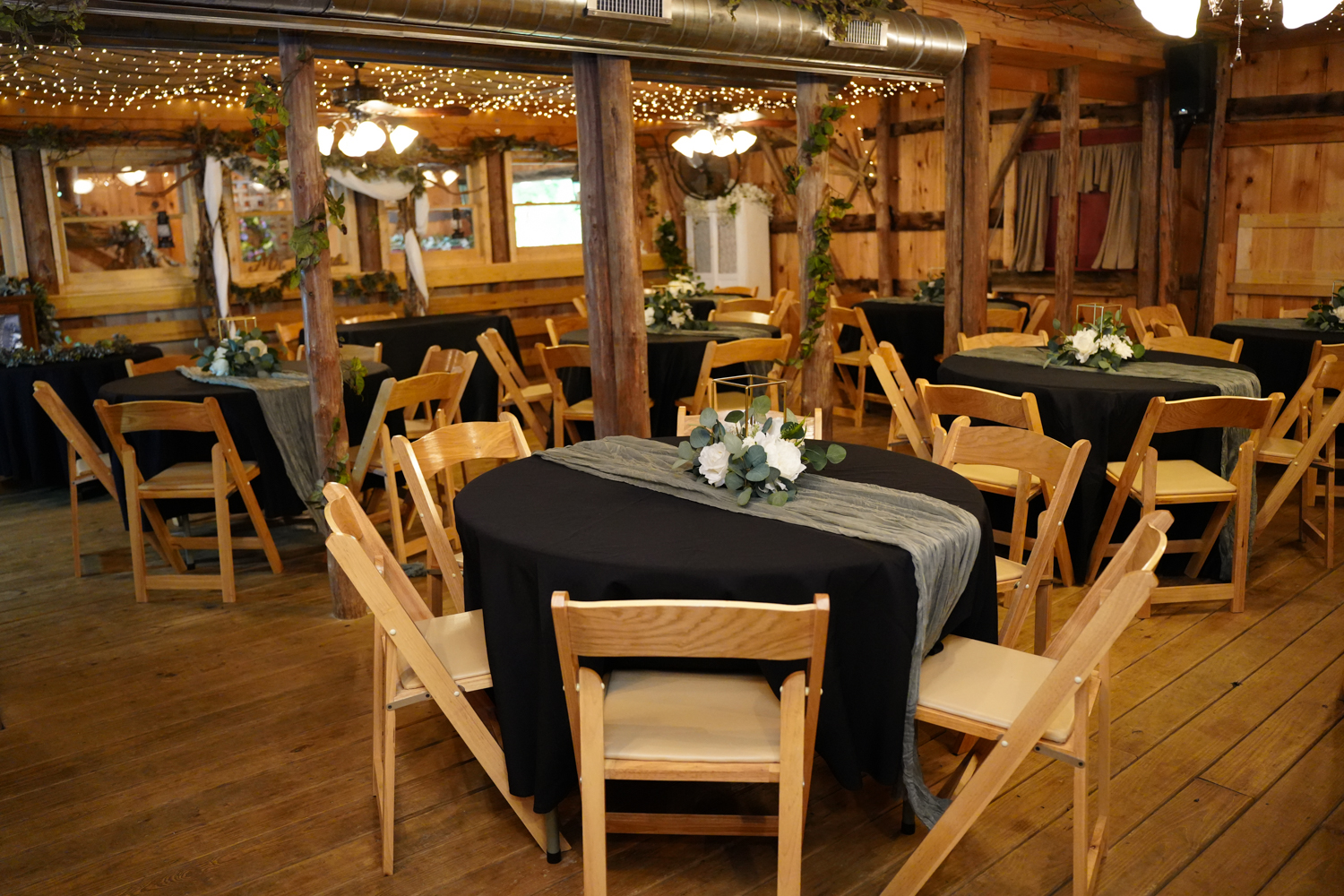 reception area set up with black table cloths and sage green runners in the barn at Honeysuckle Hills in Pigeon Forge