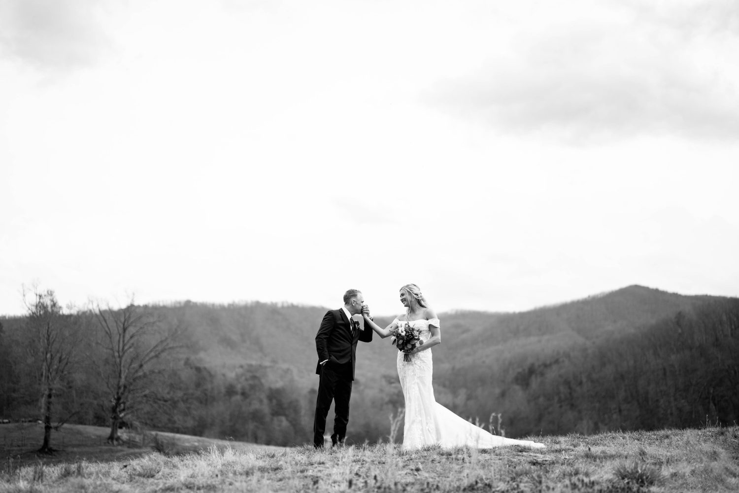 groom kissing his bride's hand during their wedding photo session at the mountain adventure site at Honeysuckle Hills