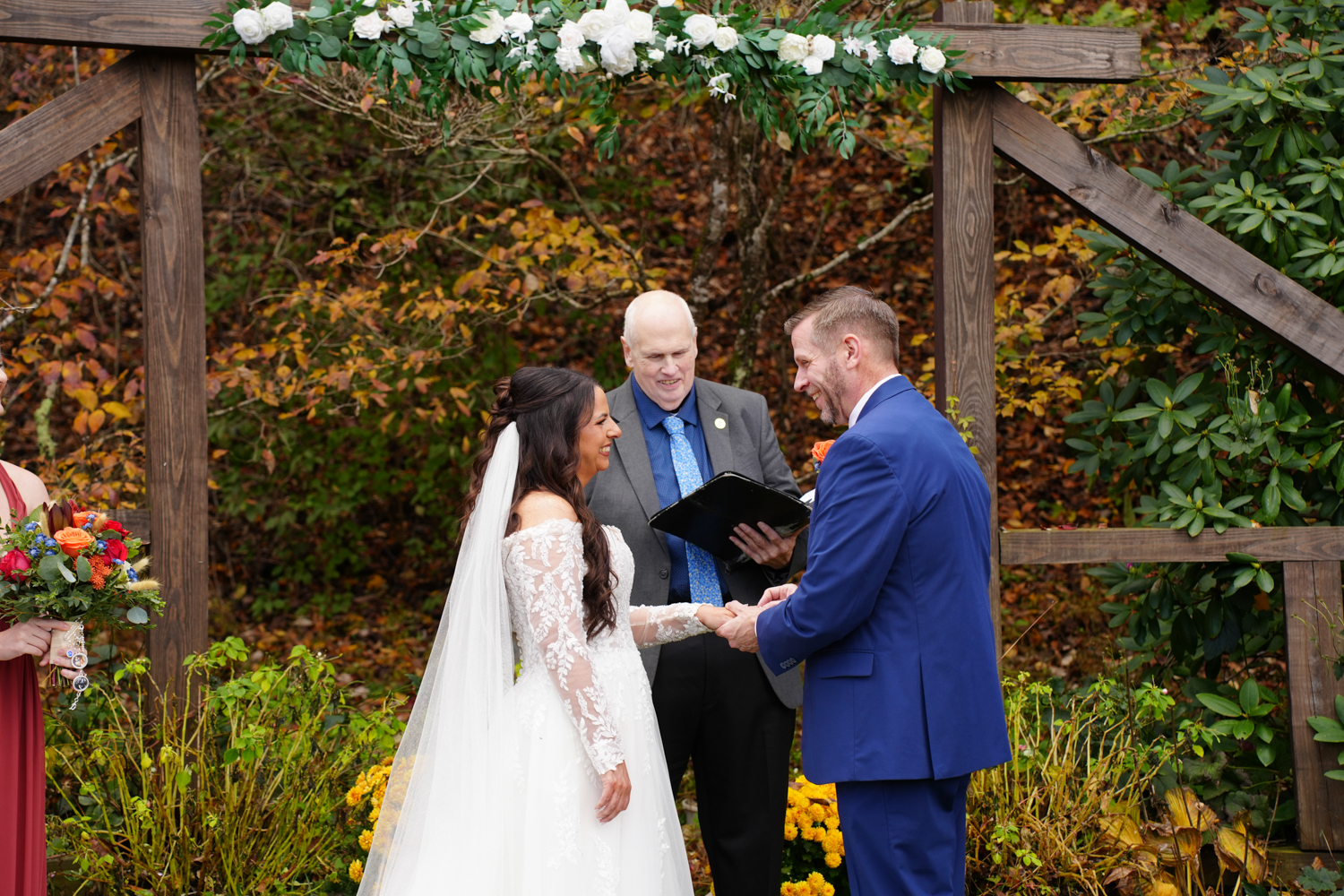 Officiant leading the ring exchange at the outdoor ceremony site called creekside ridge at Honeysuckle Hills in the fall