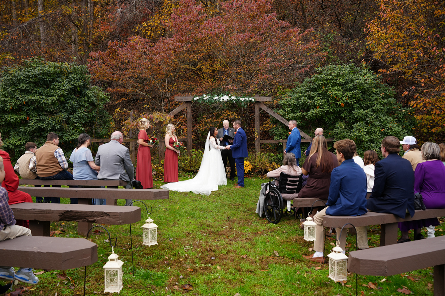peak fall leaf color outdoor wedding ceremony in the Smoky Mountains at Honeysuckle Hills at a wooden arbor with log benches and a lanterns hanging on shepherd hooks