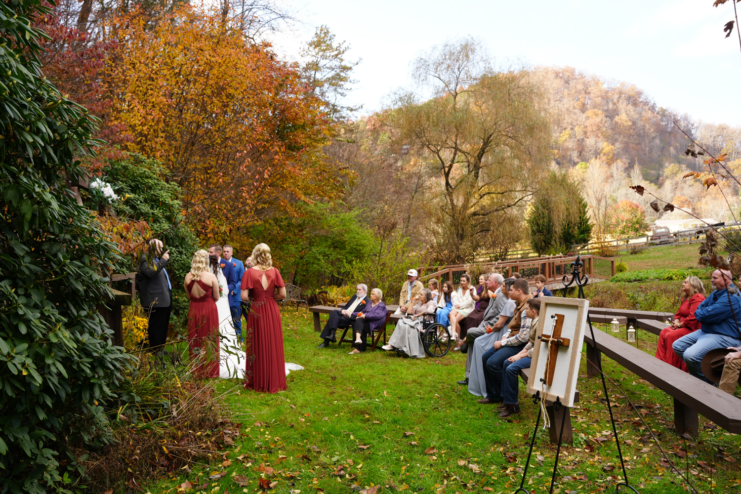Outdoor wedding ceremony in the Smoky Mountains during peak fall leaf color with a unity cross