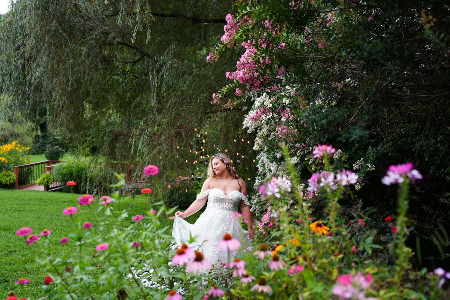 Honeysuckle Hills Wedding Venue Pigeon Forge (16) Summer wedding gardens at Honeysuckle Hills with a bride holding the hem of her wedding gown among zinnia, cleome and crepe myrtles