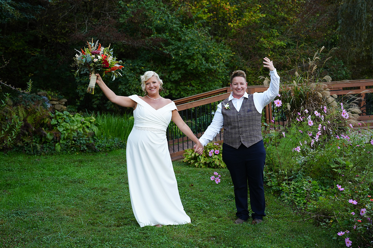Two brides celebrating on their wedding day in the gardens at Honeysuckle Hills
