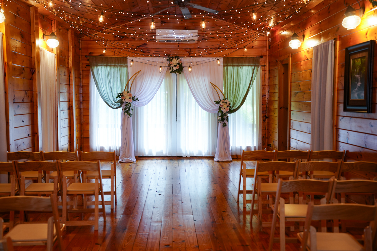 Wedding chapel inside the historic Honeysuckle Hills barn in Pigeon Forge decorated with string lights and curtain swags