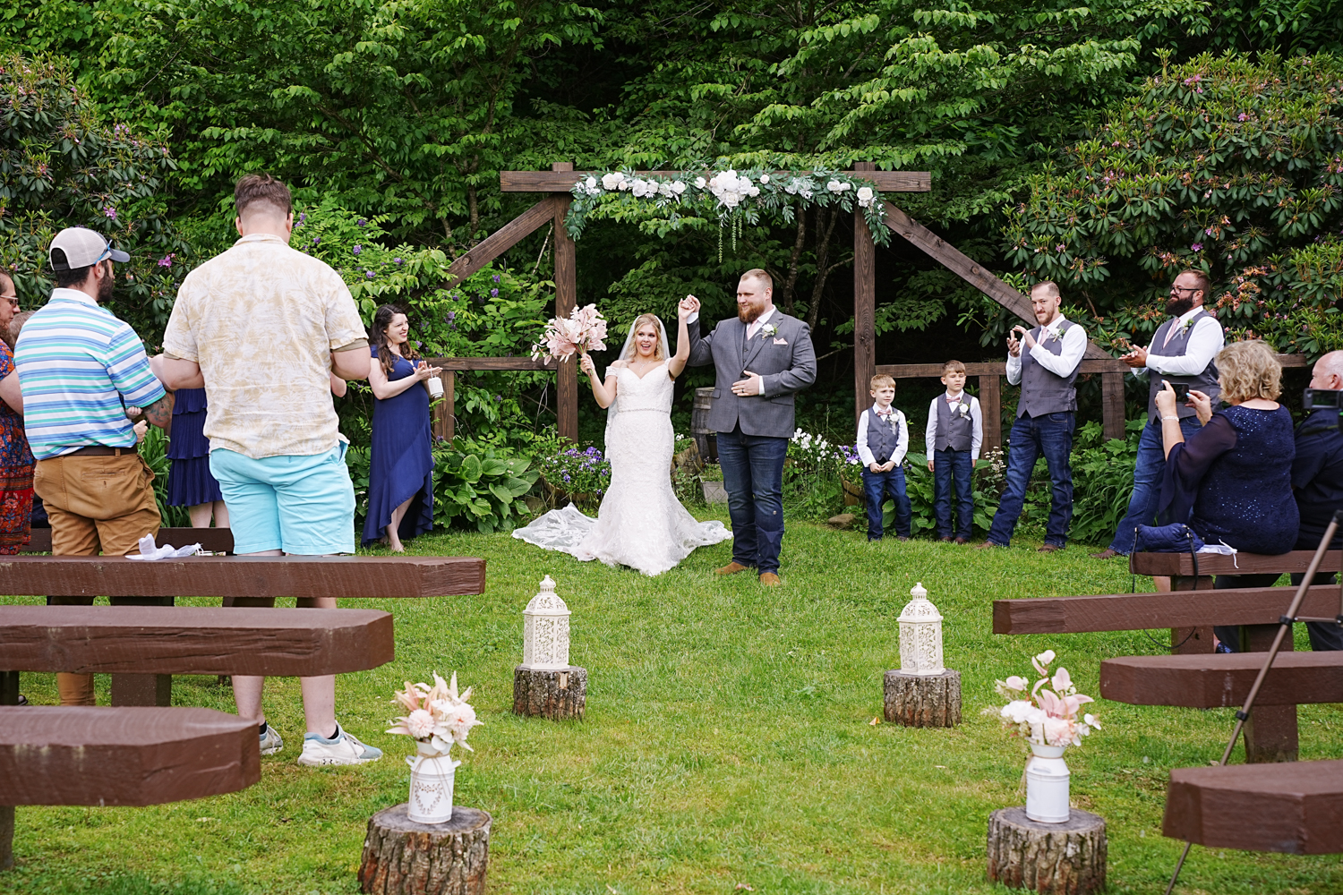 Happy couple raising their arms with joy after their ceremony at a wooden arbor in the wedding gardens at Honeysuckle Hills in Pigeon Forge