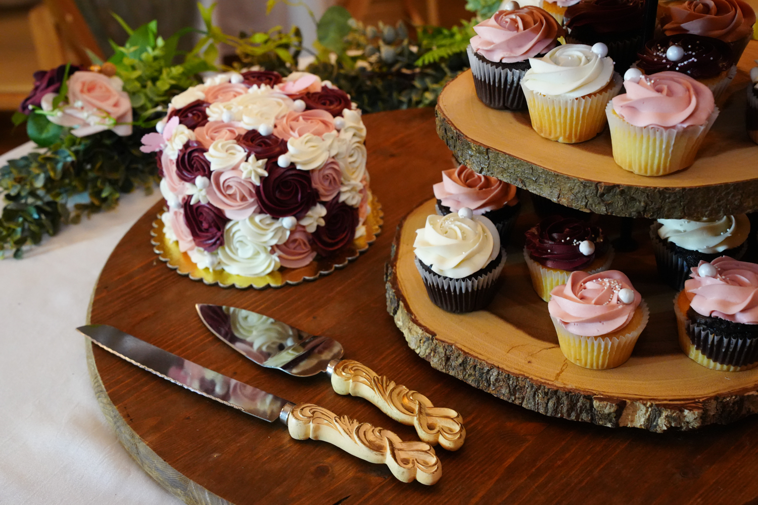 sliced log display with cupcakes and a six inch wedding cake in multiple colors with a fancy cake cutting knife